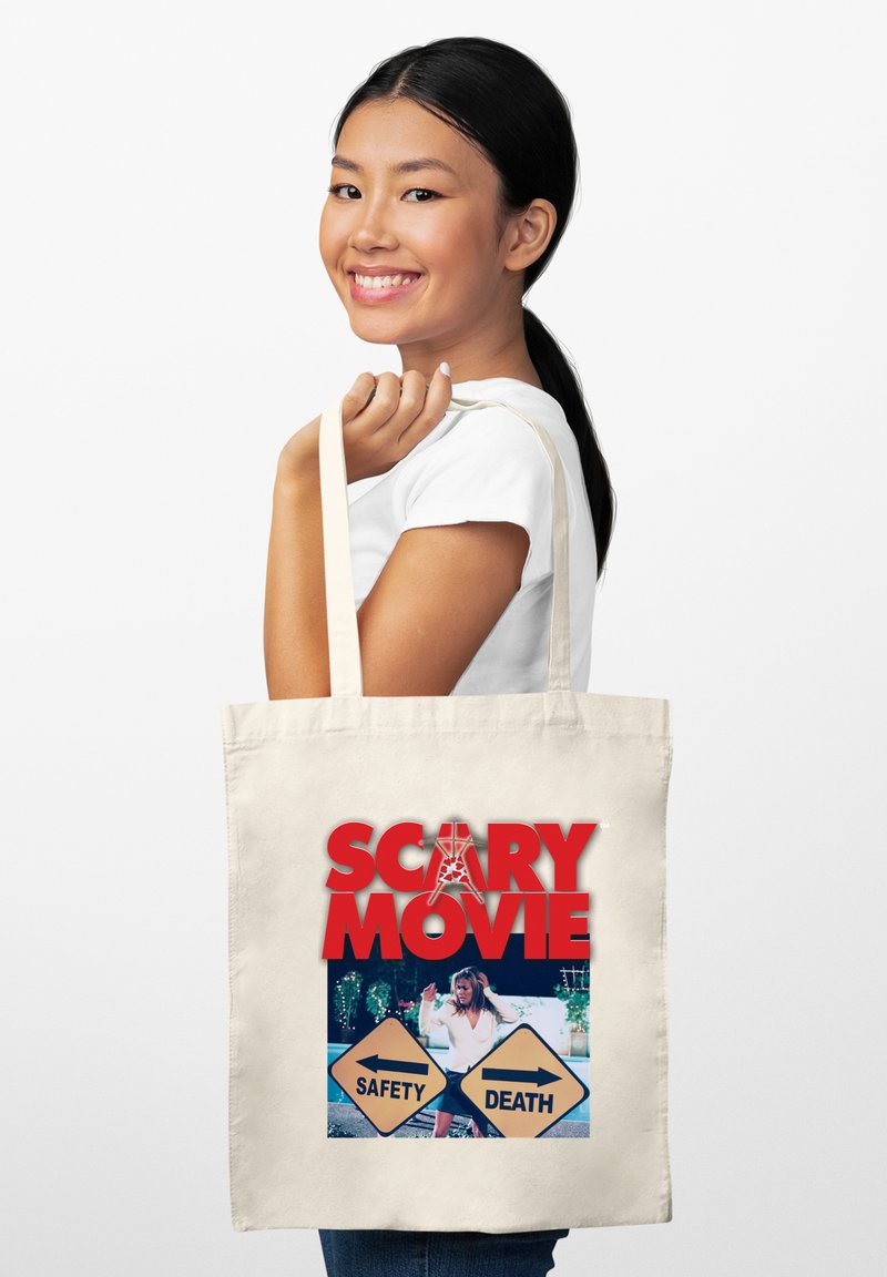 Bolsa de tela en color crema con un gran gráfico rojo que dice "PELÍCULA DE TERROR" y una imagen impresa que presenta dos letreros direccionales etiquetados como "SEGURIDAD" y "MUERTE".