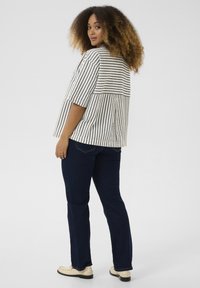 Top a maniche corte a righe in bianco e grigio, con una vestibilità comoda e un dettaglio della spalla sul retro, abbinato a jeans dritti blu scuro.