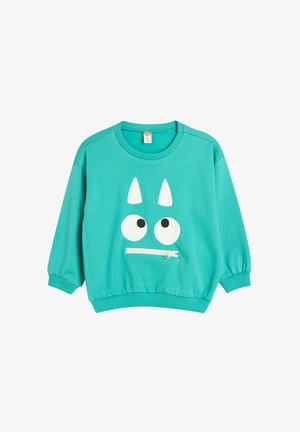 Turkusowy sweter z okrągłym dekoltem, długimi rękawami i wzorem twarzy z białymi oczami i rogami. Zawiera kieszeń z przodu na zamek błyskawiczny.