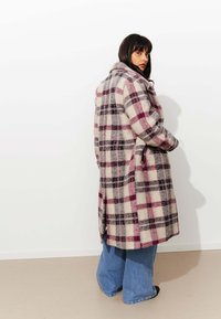 Manteau en mélange de laine à carreaux dans des tons crème, bourgogne et gris, avec un col, des manches longues et une coupe décontractée au design mi-long.