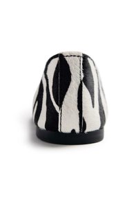 Bailarina con estampado de cebra en blanco y negro, con una parte superior suave y texturizada y una punta plana y redondeada. Diseño minimalista y suela negra sólida.