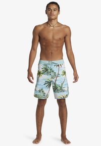 Board shorts in light blue with a tropical print. Features palm trees and ocean waves. Drawstring waist and textured fabric.
