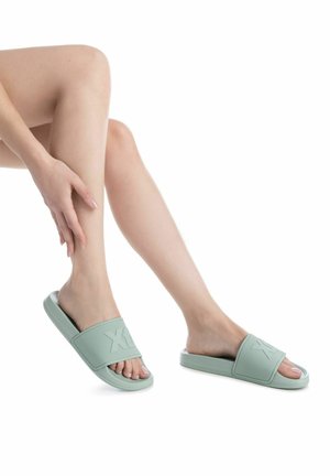 Las sandalias de goma verde claro tienen una correa texturizada y detalles del logo. Diseño destalonado con una suela plana, aptas para un uso casual.