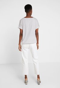 Randig kortärmad topp med en lös passform, tillverkad av lätt tyg. Matchas med vita byxor och klackar i djurprint för kontrast.