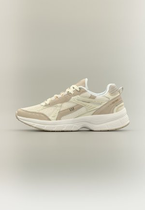 Sneaker beige e bianca con lacci, pannelli in mesh e camoscio, suola spessa e strutturata e logo "GAP" sul lato.