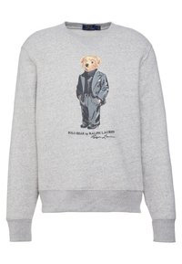 Grå sweatshirt med en grafik av en björn i en randig kostym. Rund hals, ribbade muddar och nederkant. Avslappnad stil med ett livligt tryck.