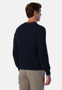 Suéter de canalé azul marino con mangas largas y un cuello redondo, que muestra un tejido texturizado y puños ajustados. La vista trasera presenta líneas limpias.