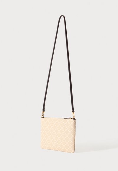 Petit sac bandoulière beige avec un léger motif losange et une longue sangle fine marron foncé suspendu sur un fond clair uni.