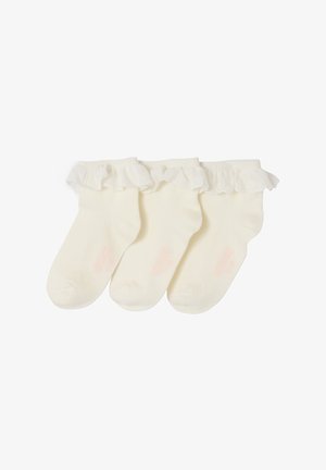 Three cream-colored baby socks with frilly, lace-trimmed cuffs arranged side by side on a white background.