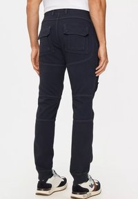Pantaloni cargo blu scuro realizzati in misto cotone, con due tasche posteriori, cuciture rinforzate, vestibilità affusolata e polsini elasticizzati.