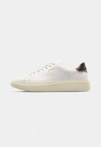 Witte sneaker met een glad leren bovenwerk, voorzien van een tan en zwart leren hieltab, ronde veters en een chunky beige rubberen zool. Gouden logo detail.