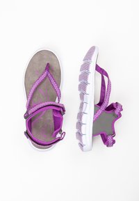 Purple sandals with a textured gray sole, featuring patterned straps and a white outsole. The design includes adjustable ankle supports.