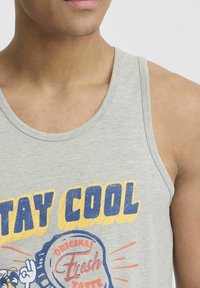 Szürke pamut ujjatlan felső, látványos grafikával, amelyen a "STAY COOL" felirat és egy üvegkupak minta található, kerek nyakkivágással.