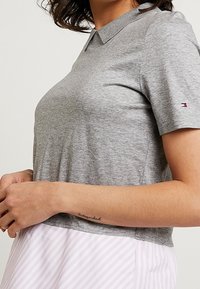 Polo shirt grigia a maniche corte con colletto classico e bordo a costine in contrasto, con un piccolo logo sulla manica sinistra.