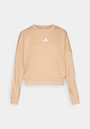 Beige cropped sweatshirt laget av myk stoff med rund hals, med en hvit Adidas-logo og hvite striper langs ermene.