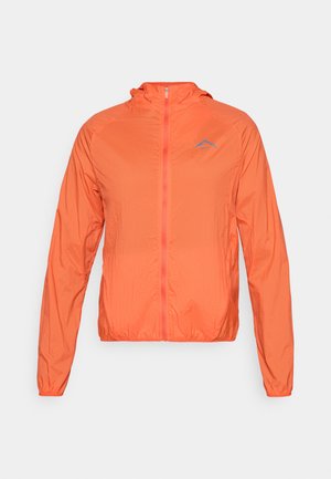 Veste légère orange avec capuche, fermeture éclair complète et poignets élastiques. Elle présente un logo bleu sur la partie gauche de la poitrine.