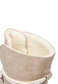 Botină din suede bej cu captuseală moale din fleece crem, guler rotund și sireturi crem contrastante. Dispune de detalii cusute de-a lungul marginilor.