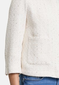 Witte textuurjacket met een licht geopende kraag, driekwartmouwen en een voorzak; beschikt over subtiele metallic accenten.
