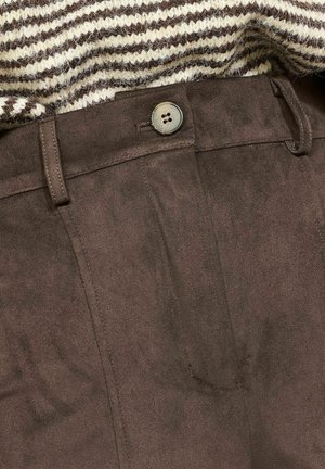 Bruine suede-achtige broek met een soepele textuur, voorzien van een voorknoop en riemlussen, gedeeltelijk bedekt door een gestreepte gebreide trui.