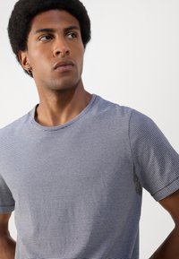 Gestreepte T-shirt met korte mouwen in marineblauw en wit, met een ronde hals. Zacht, glad materiaal met een ontspannen pasvorm en een subtiele textuur.