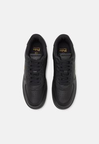 Svarta atletiska sneakers med perforerad design, texturerade läderöverdelar, tonade snören och guldlogotypdetalj vid tungan.