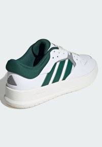 White athletic shoe with green accents, featuring three stripes, a padded collar, and a textured sole marked "CLOUDFOAM." Rounded toe design.