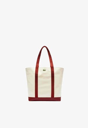 Sac en toile avec des bretelles et un fond rouges. Présente un logo brodé vert. Forme rectangulaire, design robuste et texture lisse.