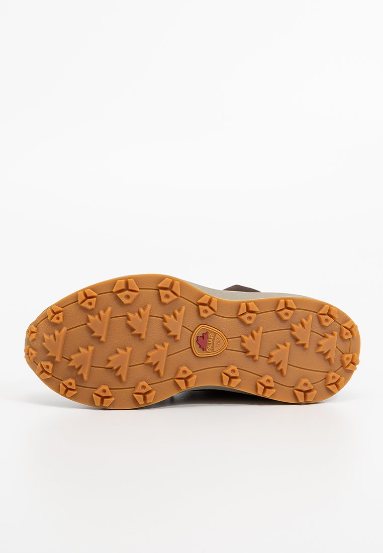 La suela del zapato presenta un material de goma texturizado en naranja con clavos en forma de tres puntos y un logotipo central. El color es predominantemente beige y marrón.