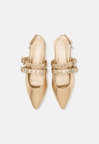 Kultaiset metalliset slingback-kengät, joissa on terävät varpaat, ja joissa on kaksi hihnaa, joissa on pyöreitä aukkoja sekä hopeansävyiset soljet. Sileä pinta.