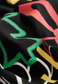 Tissu noir avec des motifs abstraits en vert, rouge, jaune et blanc. La texture semble lisse avec un léger stretch.