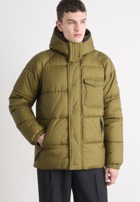 Jasnozielona kurtka puchowa z wysokim kołnierzem, zapinana na zamek błyskawiczny po bokach oraz guziki z przodu, o teksturowanym, pikowanym wykończeniu.