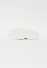 Hvit sneaker såle med teksturert grep mønster, med preget merkevarenavn "ALMA EN PENA," designet for grep og holdbarhet.