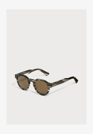 Lunettes de soleil rondes avec verres marron foncé et montures en plastique transparent vert olive marbré sur fond blanc.