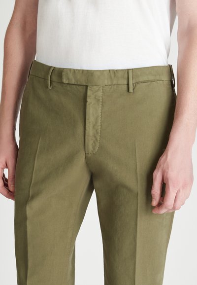 Pantalones verde oliva con una textura suave, que presentan un ajuste slim, una cremallera en la bragueta y sutiles bolsillos laterales. La cinturilla incluye passadores para cinturón.