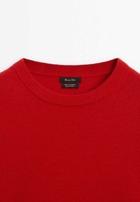 Punainen kashmir-neulepaita pyöreällä kaula-aukolla ja ribatulla kauluksella. Mukana etiketti, joka osoittaa 100 % kashmiria. Tasainen tekstuuri koko pUser peitossa.