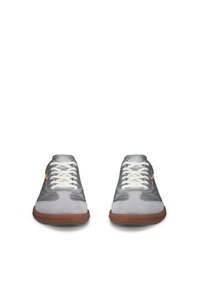 Paire de baskets grises et blanches avec des semelles marron et des lacets blancs, vues de face sur un fond blanc.