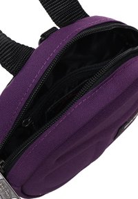 Borsa di stoffa viola con un'esterno testurizzato, dotata di una tasca interna nera e chiusura con zip; include una tracolla per il trasporto.