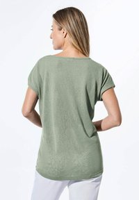 Mintgrünes kurzärmliges Oberteil mit lockerer Passform, Rundhalsausschnitt und weicher Textur. Nahtloses Rückendesign ohne sichtbare Verschlussdetails.