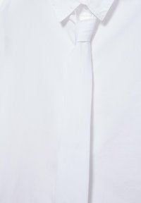 Hvid skjorte med en pænt bundet hvid slips, centreret under en spids skjortekrave.