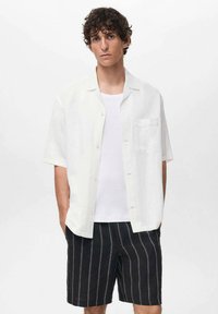 Witte korte mouwen knoopshirt, met lichte stof, met een borstzakje, gecombineerd met zwarte gestreepte shorts, knielengte, casual ontwerp.