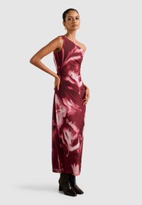 Epäyhtenäinen yksiolkaiminen mekko burgundin värissä, jossa on kukkakuosi, valmistettu sileästä kankaasta, yhdistetty mustiin nilkkakorkoihin.