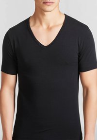 T-shirt nero a maniche corte con scollatura a V, realizzato in un materiale liscio ed elastico, con un design aderente e dettagli di cucitura discreti.