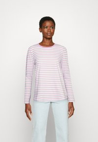 Camisola de manga longa às riscas em lilás claro e branco. Tecido suave com decote redondo e corte descontraído. Jeans azul claro usados em baixo.