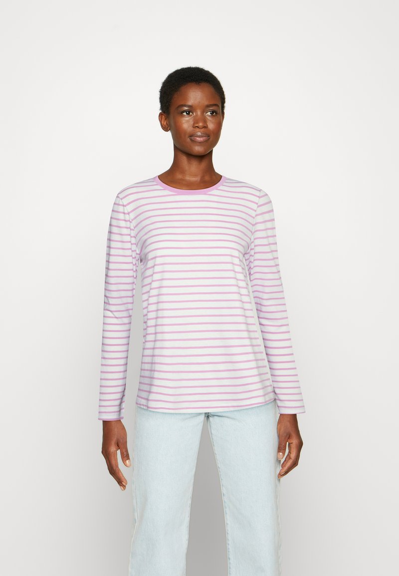 Camisola de manga longa às riscas em lilás claro e branco. Tecido suave com decote redondo e corte descontraído. Jeans azul claro usados em baixo.