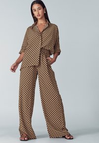 Brown patterned outfit featuring a loose-buttoned shirt and wide-leg pants. The fabric is lightweight with a soft texture.