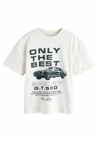 T-shirt in cotone bianco con stampa grafica di un'auto nera Shelby G.T.500 e testo in grassetto. Vestibilità ampia con collo rotondo e maniche corte.