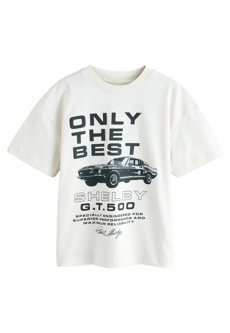 T-shirt in cotone bianco con stampa grafica di un'auto nera Shelby G.T.500 e testo in grassetto. Vestibilità ampia con collo rotondo e maniche corte.