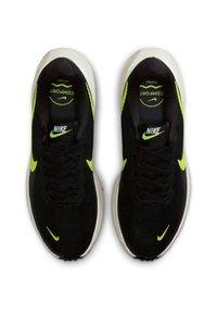 Mustat Nike-jalkineet neon-keltaisilla yksityiskohdilla, joissa on hengittävä verkko-osa, tekstuuriset nauhat ja pehmeä pohja, merkitty "Mukavuus".