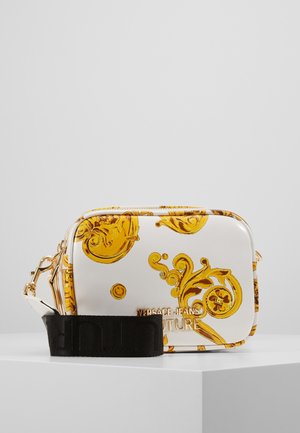 Biała prostokątna torba na ramię z złotymi wzorami barokowymi, złotą plakietką z logo i szerokim czarnym regulowanym paskiem na białej powierzchni.