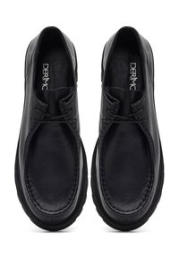Zapatos de cuero negro con puntera redondeada, que presentan un diseño cosido y un cordón minimalista. La suela es redondeada y gruesa para mayor comodidad.